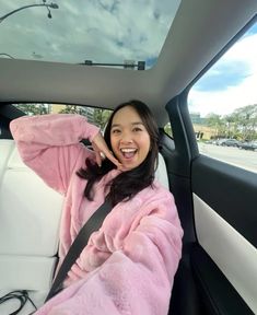 a woman sitting in the back seat of a car while talking on a cell phone