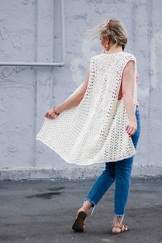 a woman walking down the street wearing a white crochet dress and brown shoes