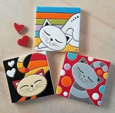 three coasters with cats painted on them sitting next to hearts and other decorative items