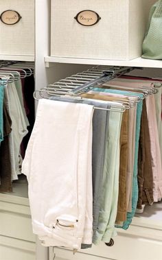 an organized closet with linens and clothes hanging on the rails, along with storage bins