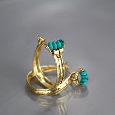 This unique and powerful design of golden crown hoop earrings came out of a session in my studio when the flattened gold filled material had been accidentally folded on both sides. The gold filled was flattened and created a rustic, ancient look that would've blended beautifully when the Aztecs were once in power. Turquoise howlite golden crown hoop earrings would be a perfect compliment for a wedding party or as a wedding gift. The earring's backs are handmade and have a very useful and comfort Turquoise Metal Hoop Earrings, Turquoise Hoop Earrings With Natural Stones, Turquoise Hoop Gemstone Jewelry, Turquoise Gemstone Hoop Earrings, Turquoise Gemstone Hoop Jewelry, Turquoise Hoop Pierced Earrings, Elegant Turquoise Hoop Earrings, Turquoise Metal Round Hoop Earrings, Turquoise Brass Hoop Earrings As Gift