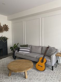 a living room filled with furniture and a guitar on the floor next to a fire place