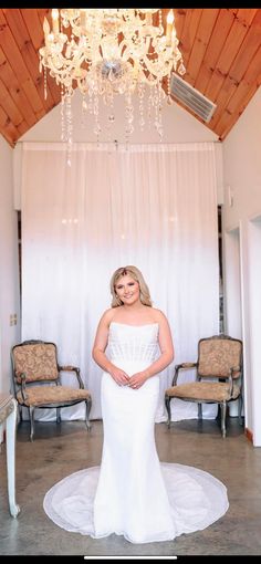 a woman in a white wedding dress posing for a photo under a chandelier