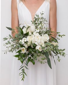 a bridal holding a bouquet of white flowers and greenery