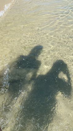 the shadow of a person standing in shallow water