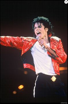 michael jackson performing on stage with his arms outstretched in front of the audience and holding a microphone