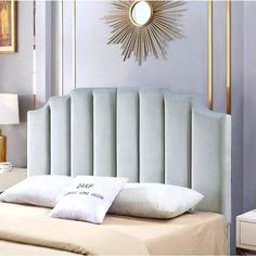 a bed with a blue headboard and pillows on top of it in a bedroom