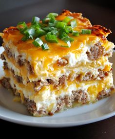 a piece of lasagna on a plate with green onions and cheese in the middle