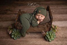 a baby sleeping in a wooden crate with succulents