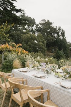 an outdoor table set up with flowers and greenery for a formal dinner in the garden