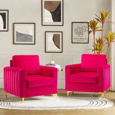 two bright pink chairs are in front of pictures on the wall and a white rug