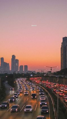 a highway filled with lots of traffic next to tall buildings at sunset or dawn in the city