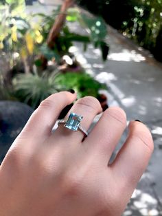 a woman's hand holding an engagement ring with a blue topazte stone