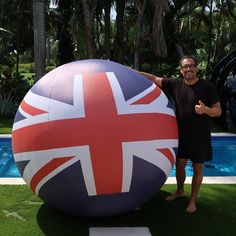 a man standing next to a giant inflatable ball with the british flag on it