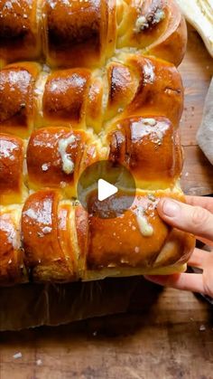 a person holding a hot cross bun on top of a wooden table