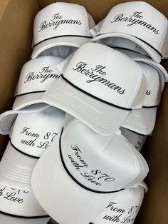 a box full of white hats with the names of different people on them in black lettering