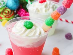 two glasses filled with colorful jello and marshmallows next to candy candies