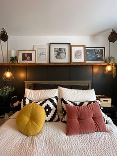 a bed with pillows and pictures on the wall above it, along with other decorations