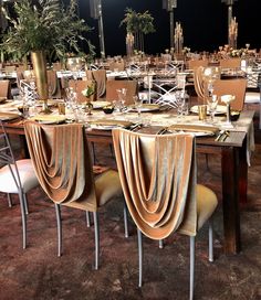 a dining room set up for an event with tables and chairs covered in gold cloths