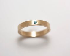 A sparkling 1.75 mm diamond cut A grade emerald flush set in a 14k gold 3 mm band in this striking minimalist ring. A flush setting gives an added amount of security to the stone. The ring can be worn by itself or as an accompaniment to another ring. If you would like an emerald of a different grade or a ring size larger than those listed, please request an estimate.  This ring would make a beautiful engagement or wedding ring. Or a "just because" ring!This is a natural emerald with no enhanceme Modern Round Emerald Ring With Tension Setting, Modern Stackable Emerald Ring For Anniversary, Modern Emerald Ring For Anniversary With Tension Setting, Modern Emerald Ring With Tension Setting For Anniversary, Modern Emerald Anniversary Ring With Tension Setting, Gold Emerald Ring With Tension Setting For Promise, Minimalist Emerald Birthstone Ring With Bezel Setting, Minimalist Emerald Diamond Ring For May Birthstone, 14k Gold Emerald Ring With Single Diamond For Promise