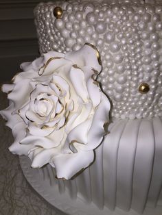 a large white rose sitting on top of a wedding cake covered in pearls and beads