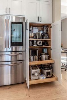 an organized kitchen with stainless steel appliances and white cabinetry, along with wood flooring