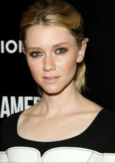 a woman with blonde hair and blue eyes wearing a black and white dress at an event