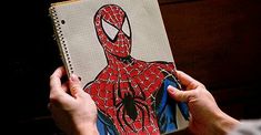 a person holding a notebook with a drawing of a spider man on it