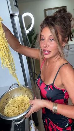 a woman holding a pot full of noodles