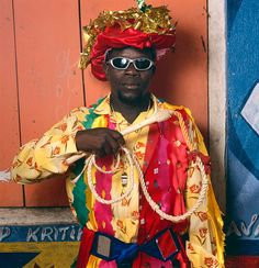 a man dressed in colorful clothing standing next to a wall