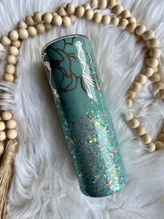 a blue and gold tumbler sitting on top of a white fur covered floor next to beads