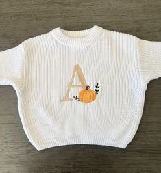 Super cute cozy sweater for fall season featuring an embroidered initial letter and pumpkin! These are machine embroidered by me. Sizes 0-6m to 4T. Sweaters are slightly oversized and have a chunky fit. Refer to measurements below. Turnaround time is currently 1-2 weeks. For these sweaters below, 18-24m is the same as 2T. White Mocha Peach Pink Dusty Blue Rose Pink Cream/Beige Lilac  Caramel Measurements 0-3 months: length-11in./bust-12in./ sleeve-6in. 3-6 months: length-11.5in./bust-13in./sleeve-7in. 9 months: length-12in./bust-14in./sleeve-7.5in 9-12 months: length-13in/bust-14.5in/ sleeve-8in 12-18 months: length-14in/bust-15.5in/ sleeve-9in. 18-24m or 2T: length-15.5in./bust-16in./sleeve-10in. 3T: length-16.5./bust-17in./sleeve-11in. 4T: length-18in./bust-18in./sleeve-11.5in. PLEASE NO White Letter Embroidery Sweater For Fall, Cute Custom Embroidered Tops For Fall, White Sweater With Custom Embroidery For Fall, Cute Tops With Custom Embroidery For Fall, White Custom Embroidered Sweater For Fall, Cute Sweater With Letter Embroidery For Fall, Cute Letter Embroidery Sweater For Fall, Oversized Fall Sweater With Letter Embroidery, Custom Embroidered Fall Sweatshirt