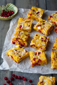 raspberry and almond squares on wax paper with berries around them, ready to be eaten