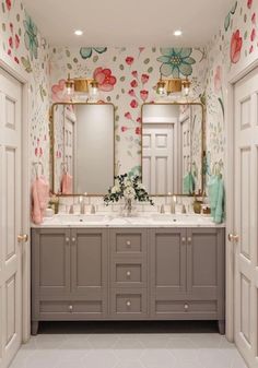 a bathroom with floral wallpaper and two sinks in front of the mirror, along with double doors leading to another room