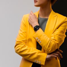 a woman in a yellow jacket with her hands on her chest looking off to the side