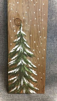 a painting on wood with white snow and a pine tree painted on it's side