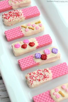 pink and white desserts are arranged in rows on a plate with sprinkles