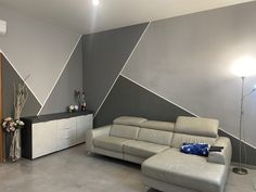 a modern living room with grey walls and white leather couches in front of an entertainment center