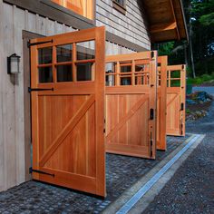 three wooden doors are open on the side of a building with brick pavers flooring