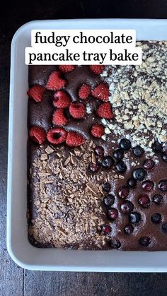 chocolate cake with berries, nuts and other toppings in a white dish on a wooden table