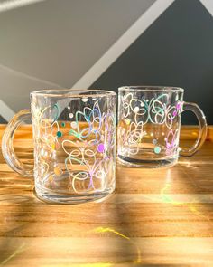 two clear coffee mugs sitting on top of a wooden table