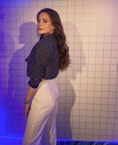 a woman standing in front of a tiled wall