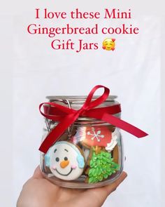 a hand holding a glass jar with cookies in it and a red ribbon around the top