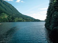 there is a boat on the water in the middle of the lake with mountains in the background