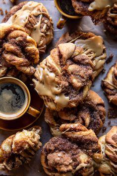 cinnamon roll cookies with icing and coffee on a table next to other pastries