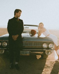 a man and woman standing in front of a car