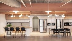 an open kitchen and dining room area in a loft apartment with exposed ceilings, wood paneling, white walls, and floor to ceiling lighting