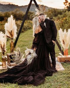 a bride and groom kissing in front of an altar with tall pamodia flowers