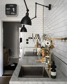 a kitchen with white brick walls and gold faucet lighting over the sink area