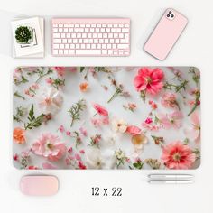 a computer mouse pad with pink flowers on it next to a keyboard and other office supplies